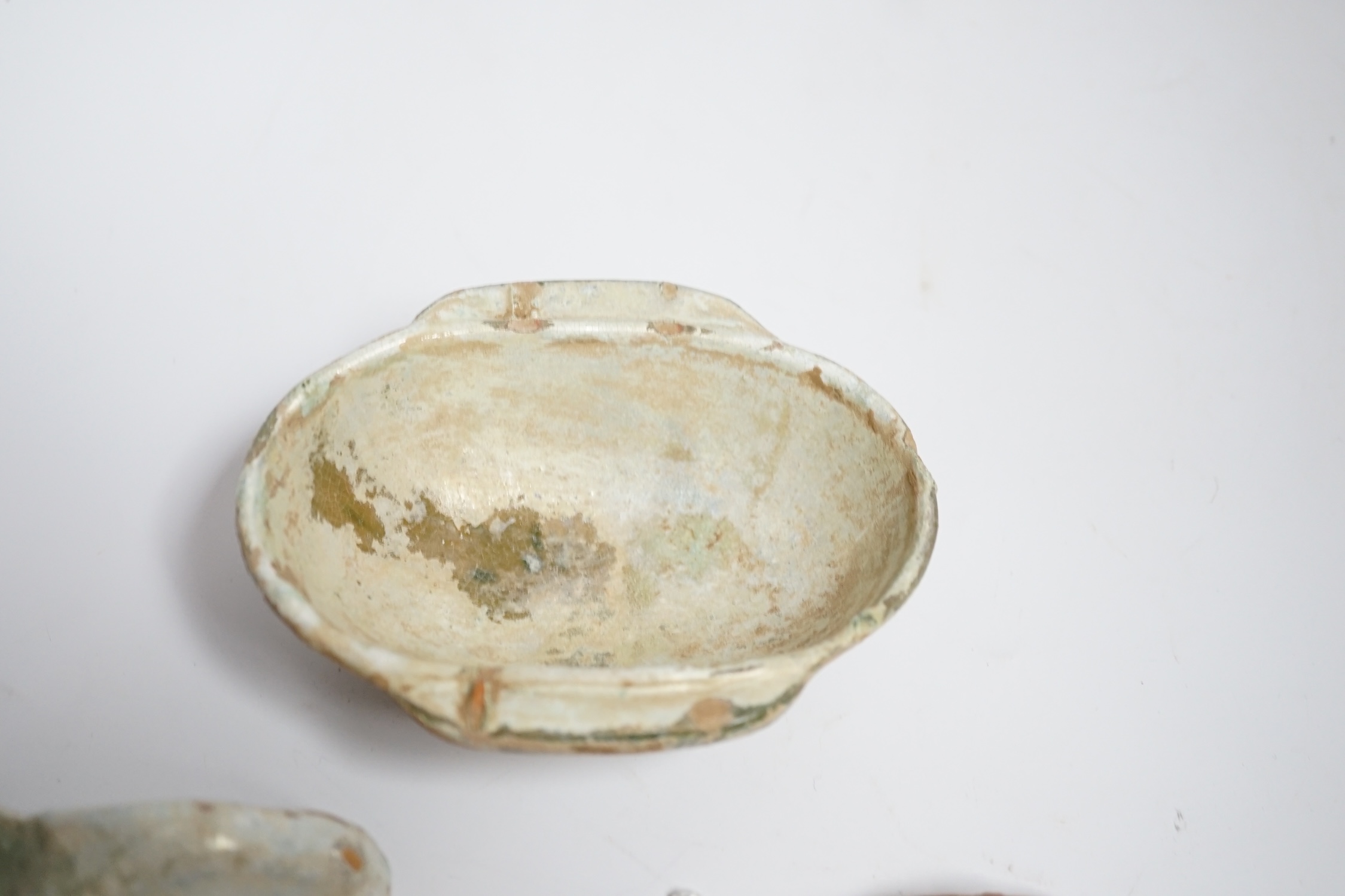 A Chinese glazed pottery ‘ear’ cup and similar spoon, Han dynasty, and a pottery figure, Song dynasty, largest 13cm wide